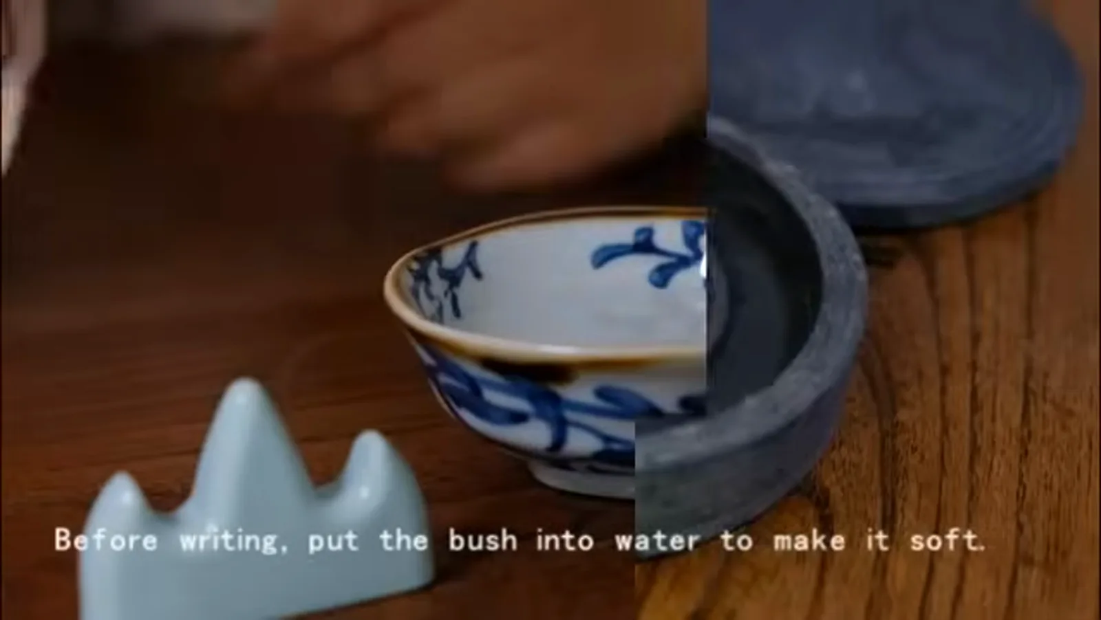 a calligraphy brush dipped into a blue-and-white bowl of water to soften its stiff bristles before loading ink for Chinese name writing