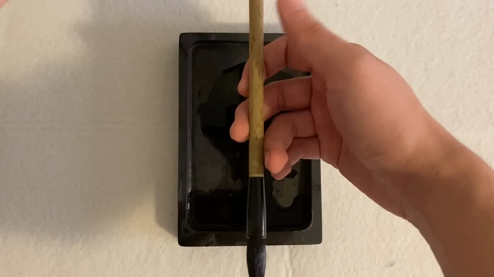 Top-down view of a right hand gripping an upright Chinese calligraphy brush firmly enough that the shaft cannot slip, with the palm kept hollow Top-down view of a right hand gripping an upright Chinese calligraphy brush firmly enough that the shaft cannot slip, with the palm kept hollow