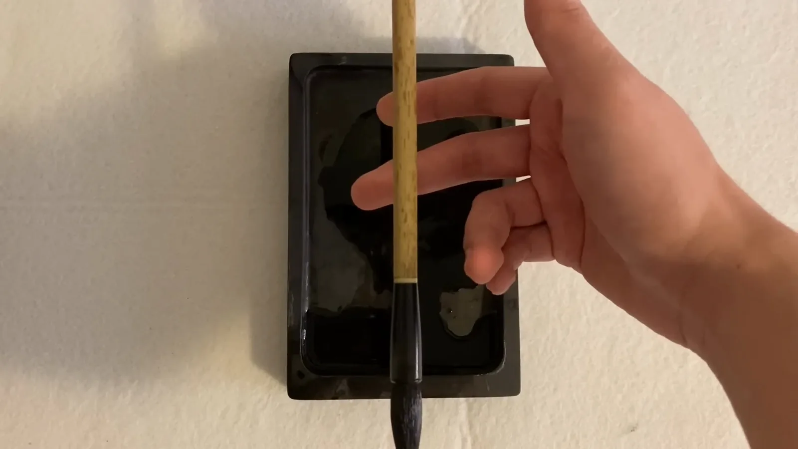 Close-up of the Chinese calligraphy brush grip with the middle and ring fingers clamping the bamboo shaft while the index finger and thumb rest naturally against it Close-up of the Chinese calligraphy brush grip with the middle and ring fingers clamping the bamboo shaft while the index finger and thumb rest naturally against it