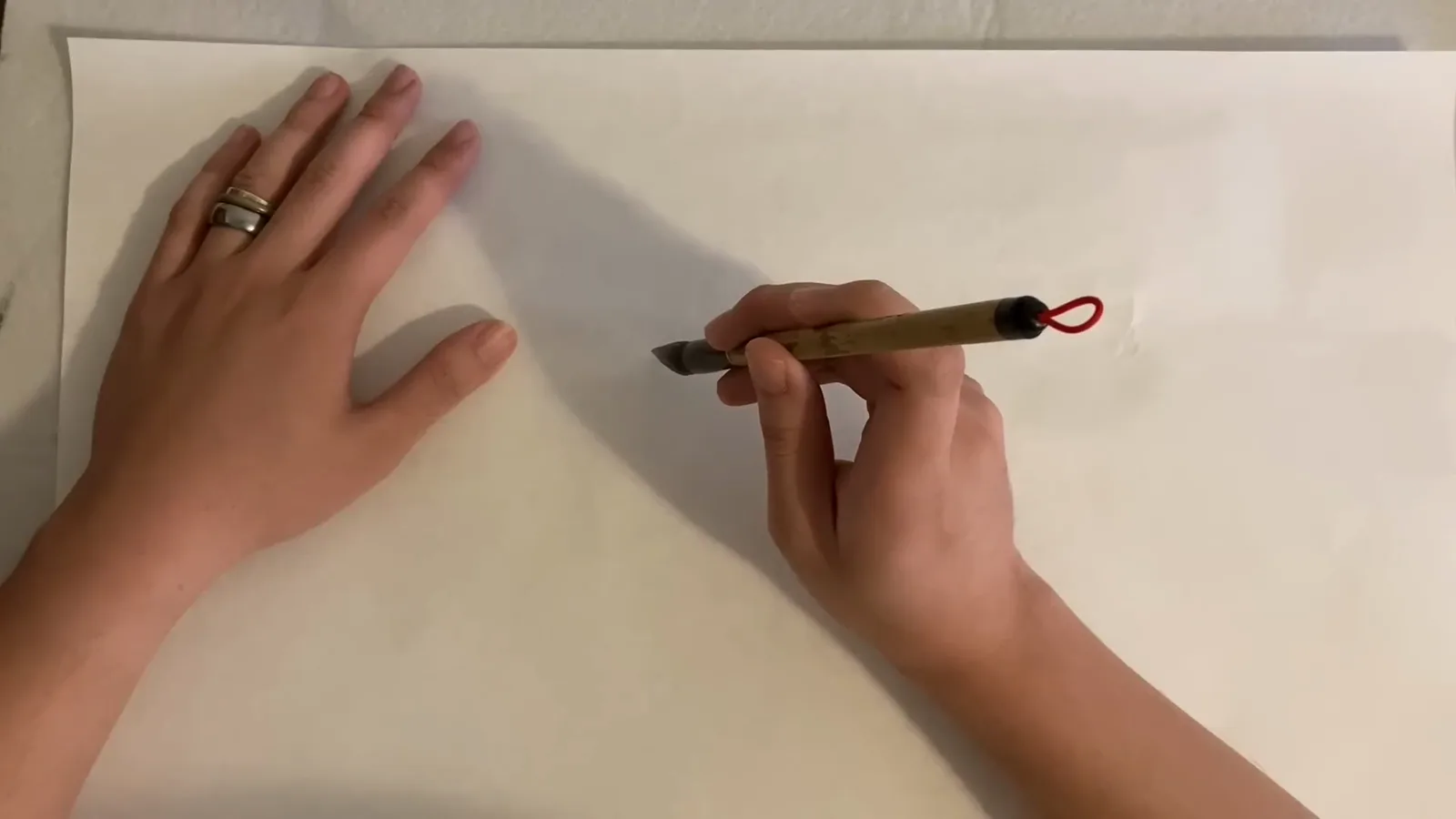 Painting the first horizontal heng stroke on rice paper with a loaded Chinese calligraphy brush kept straight while pressing down and dragging across Painting the first horizontal heng stroke on rice paper with a loaded Chinese calligraphy brush kept straight while pressing down and dragging across
