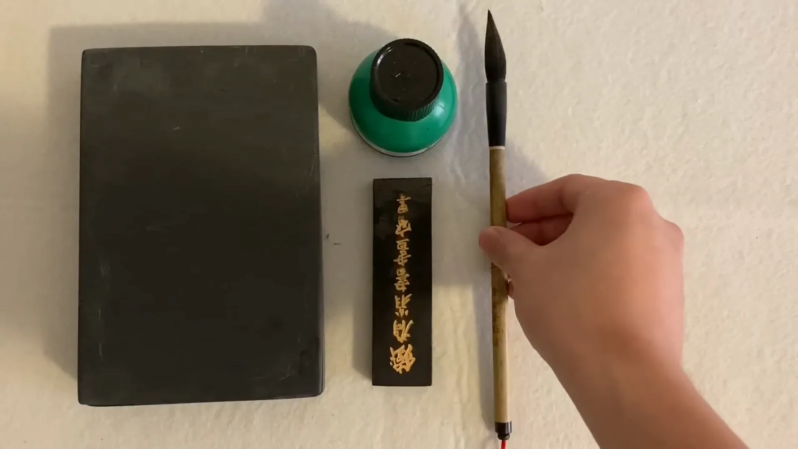 The four treasures of Chinese calligraphy laid out on white felt: a stone inkstone, a bottle of ready-made ink, a solid ink stick, and a bamboo brush The four treasures of Chinese calligraphy laid out on white felt: a stone inkstone, a bottle of ready-made ink, a solid ink stick, and a bamboo brush