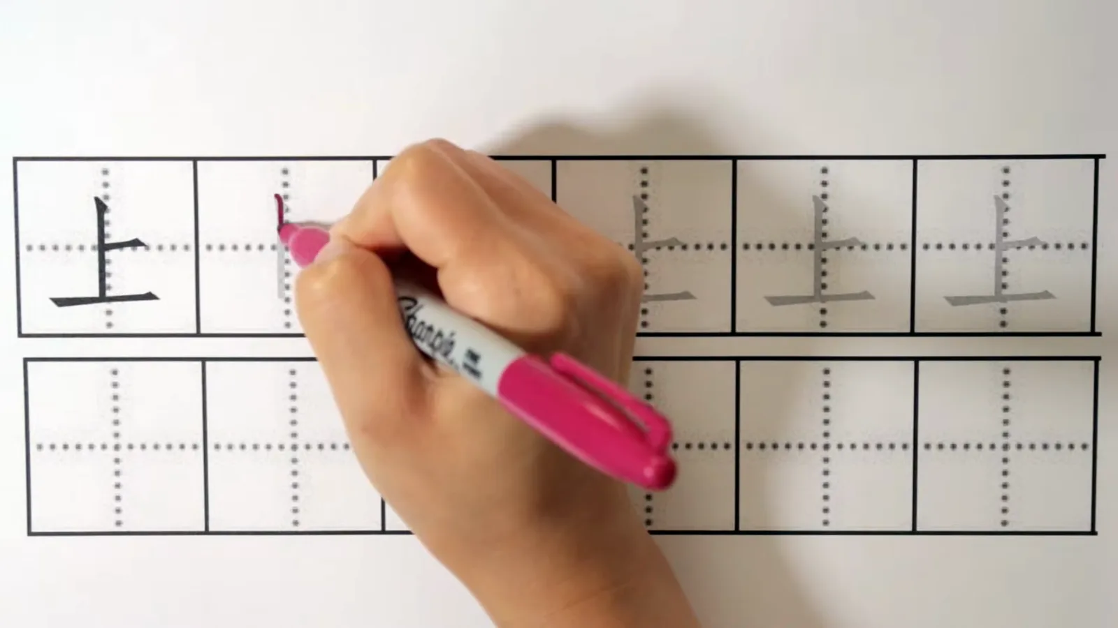 Step-by-step assembly of the character shàng up as horizontal and vertical strokes combine in the correct order on the practice grid